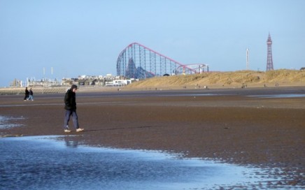 A man walking along Blackpool beach on his own