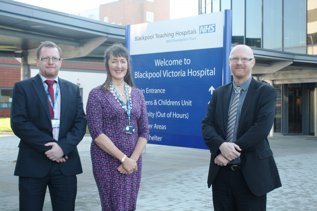 Three people standing next to a hospital sign