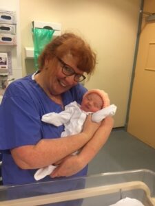 Newborn baby, Adora Hilton, held by midwife