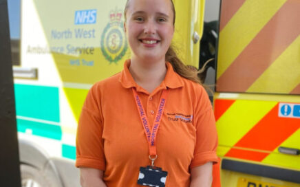 Photo of Charlotte wearing an orange Volunteers shirt outside the Emergency Department entrance