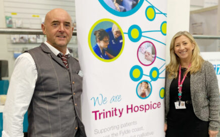 Volunteer Terry standing with Janine Hills and the Trinity Hospice banner